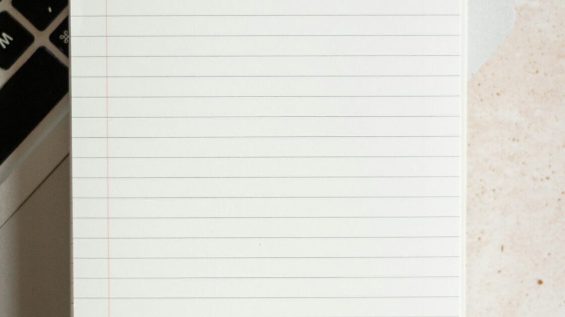 ノートパソコンとメモ帳で作業